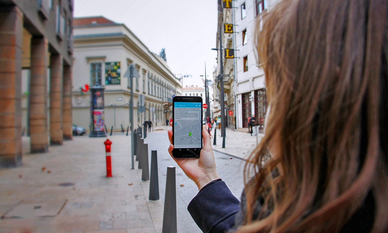 A girl holds a phone in the city; she uses the Mistory app.